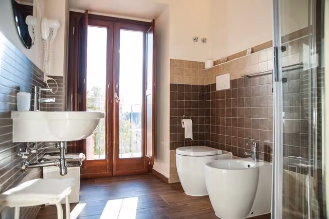 Bagno con due servizi igienici, lavandino e doccia