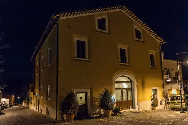 L'edificio de La Locanda di Mariella illuminato di sera, in Via Umberto I a Poggio Picenze