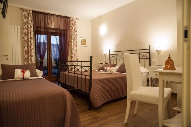 Camera matrimoniale con letti, sedia e tavolo della locanda